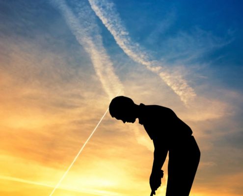 man playing golf at sunset