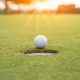 Golfer is putting golf ball on green grass at golf course for game with blur background and sunlight ray